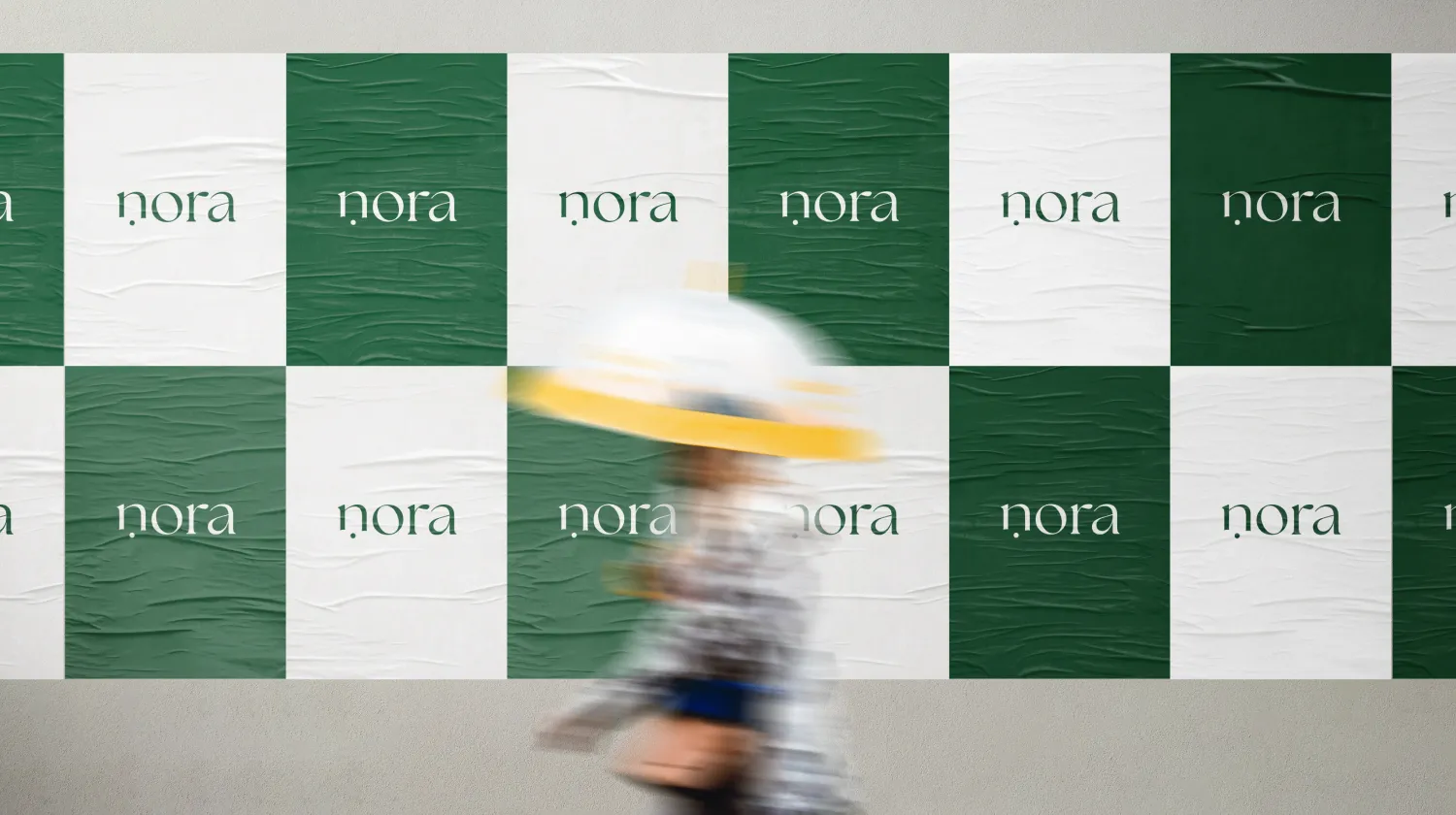 Nora logo posters in green and white pasted along a street wall
