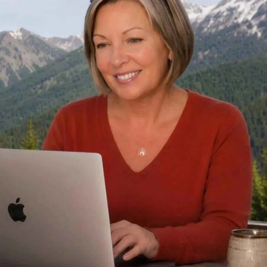 Diane Green working at a laptop outdoors with mountains behind her
