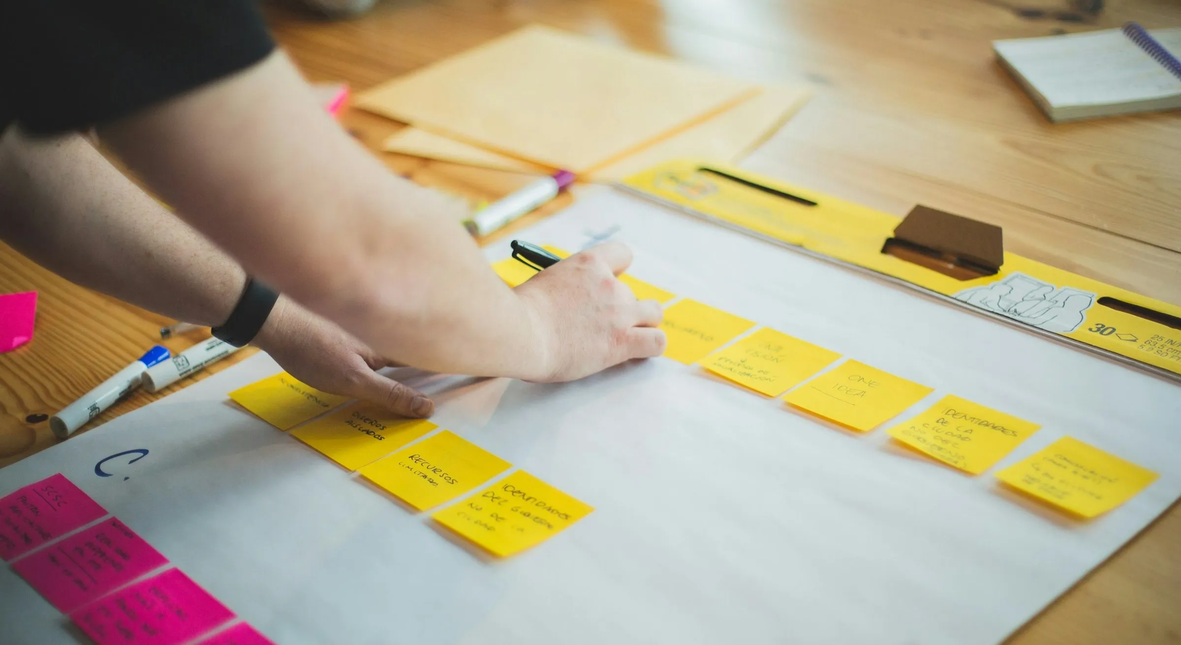A person writing on sticky notes laid out on a table in a plan